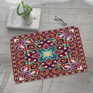 Detail of square flannel mat with mandala pattern on a light grey wooden floor