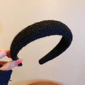 Close-up of black tweed headband with shimmering metallic threads and padded design