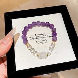 Macro shot of amethyst beaded bracelet with cat pendant in premium jewelry gift box