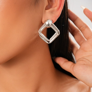 Gros plan d'une femme portant des boucles d'oreilles losanges doubles en métal argenté