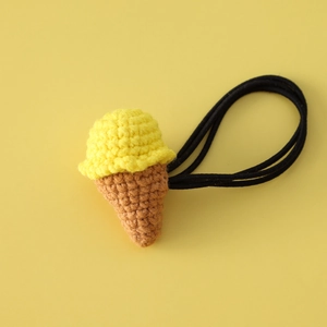 Macro detail of hand-crocheted ice cream hair tie with yellow knitting and black elastic