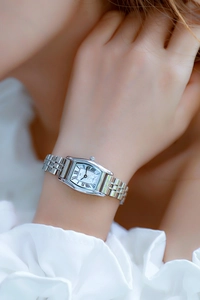 Close-up of a silver tonneau ladies watch with white dial and Roman numerals on wrist