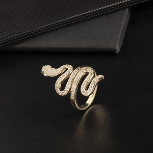 Close-up of gold-plated snake ring with white zircons and green gemstone eyes