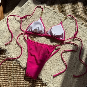 Detail of fuchsia bikini top with gold metal chain accents and white lining
