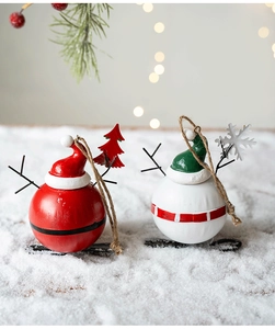 Detail view of snowman metal ornaments with snow, pine branches and warm bokeh background