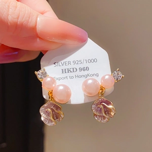 Close-up of S925 silver bow earrings with pink pearls and purple floral petals