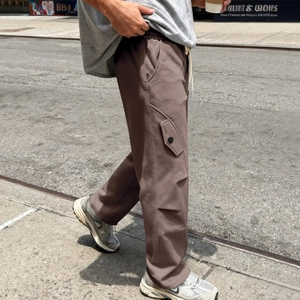 Dettaglio di pantaloni cargo marrone scuro con tasche laterali a patta in stile street