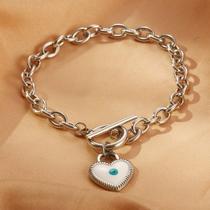 Detail eines Silberkettenarmband mit blauem Auge-Herz-Anhänger und OT-Knebelverschluss