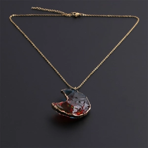 Gros plan d'un pendentif demi-lune plaqué or avec une pierre semi-précieuse irisante