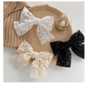 Detailed view of lace bow hair clips in white, beige and black on a decorative tray