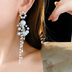 Elegant gold tassel earrings with pearl flower studs and long metallic fringe chains