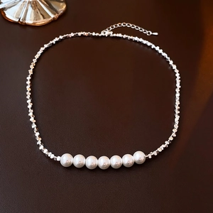 Détail d'un collier avec perles métalliques argentées et sept perles blanches