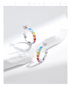 Detail shot of s925 silver hoop earrings with colorful enamel hearts on white stone