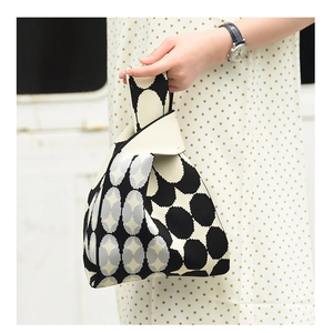 Detail of minimalist knit handbag featuring black and white geometric jacquard patterns