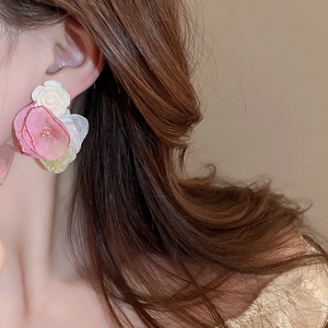 Close-up of pink and white lace flower earrings with beads on a model wearing them