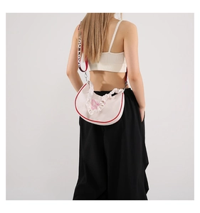Détail du sac croissant avec poignée à volants et broderie de papillon