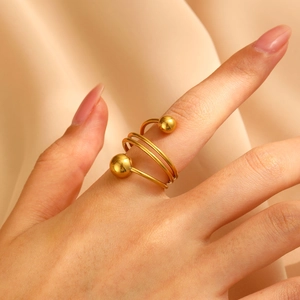Detail of a gold spiral multi-layer ring with polished metal spheres on silk background