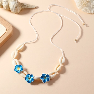 Détail du collier de fleurs en nacre avec perles bleues et jaunes sur fond style plage