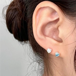 Close-up of minimalist heart stud earrings with blue and clear cubic zirconia stones