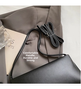 Detail view of the sleek black leather underarm bag with thin shoulder strap on grey blazer