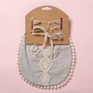 Détail d'un ensemble bavoir gris avec dentelle blanche et bandeaux à nœuds assortis