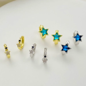 Macro view of gold and silver star earrings with zircon and colorful enamel inlay