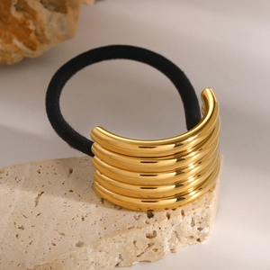 Macro shot of gold multi-layered metal hair cuff with ribbed texture on natural stone