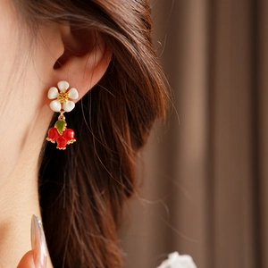 Close-up of vintage flower earrings with red pomegranate charms and gold finish details