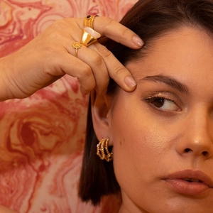 Detailed close-up of C-shaped gold-plated stainless steel earrings with sparkling accents