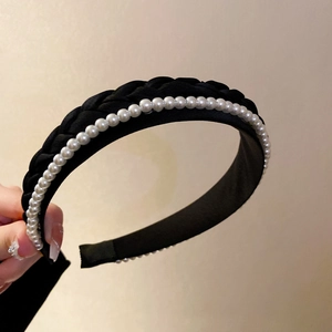 Detailed close-up of a black woven headband with elegant white pearl embellishments