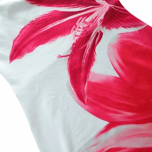Detailed close-up of vibrant red lily floral print on white summer dress fabric