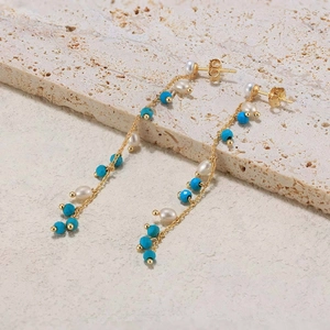 Detail of bohemian long tassel earrings with freshwater pearls and blue turquoise beads