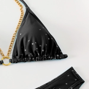 Detail of black polka dot bikini top with luxury gold chain strap and metal rings