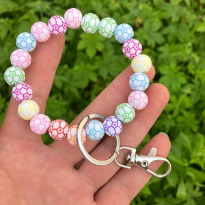 Close-up of colorful soccer bead wristlet keychain with silver metal clip on grass
