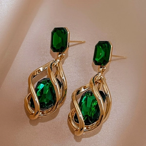 Detail view of emerald green gemstone set in a vintage gold-tone twisted hollow frame