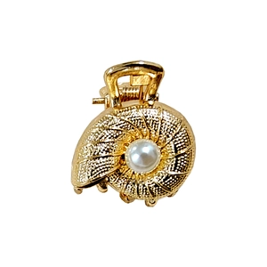 Detailed close-up of golden shell-shaped hair claw clip with a centered white pearl