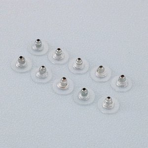 Minimalist stainless steel bullet earring backs with clear silicone disc pads on grey surface