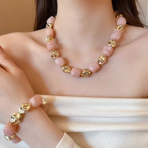 Macro view of pink marble beads and twisted gold polished metal on bracelet and necklace