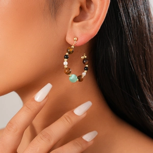 Detail of vintage gold hoop earring with tiger eye, pearls and mixed beads on model