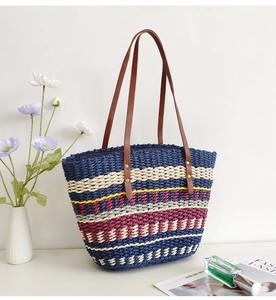 Detail of colorful striped straw tote bag with brown leather handles and summer accessories