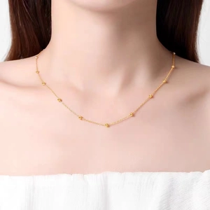 Close-up of minimalist gold beaded necklace worn by a model with a clean aesthetic look
