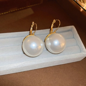 Gros plan de boucles d'oreilles perles blanches avec crochets dorés sur velours