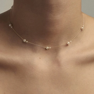 Close-up of 18k gold stainless steel necklace with delicate pearls on a female neck