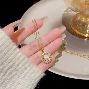 Golden sunburst star necklace with sparkling zircons held by hand in elegant setting