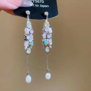 Detailed macro of silver zircon heart earrings with colorful stones and pearl drops