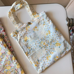 Detail of floral cotton handbag showing yellow flower pattern and antique bronze button