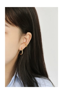 Close-up of elegant gold-plated hoop earrings and bead ear cuff worn by a model