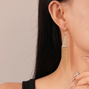 Détail de boucles d'oreilles triangles dorées avec glands en strass brillants sur mannequin