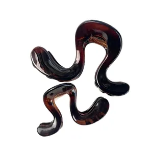 Tortoiseshell s-shaped hair claw clips set with gold springs on white background