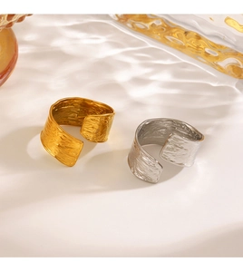 Detailed close-up of wide hammered texture rings in gold and silver with water reflections